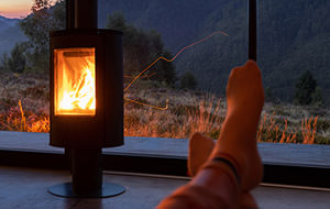 Ein brennender Kamin im Wohnzimmer mit Blick aus dem Fenster